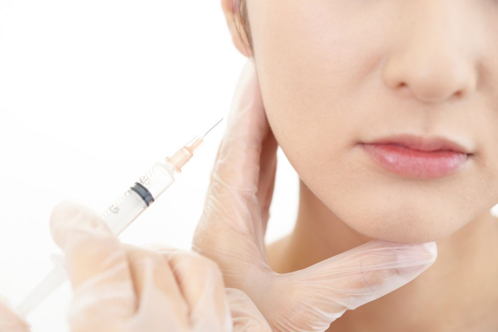 Closeup of woman receiving Botox injection in the side of her face.
