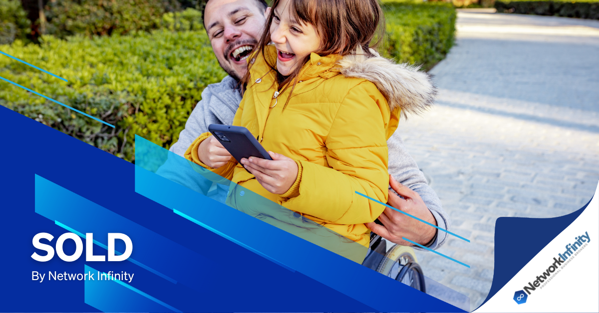 an NDIS participant woman is holding a little girl in her arms while looking at a tablet.