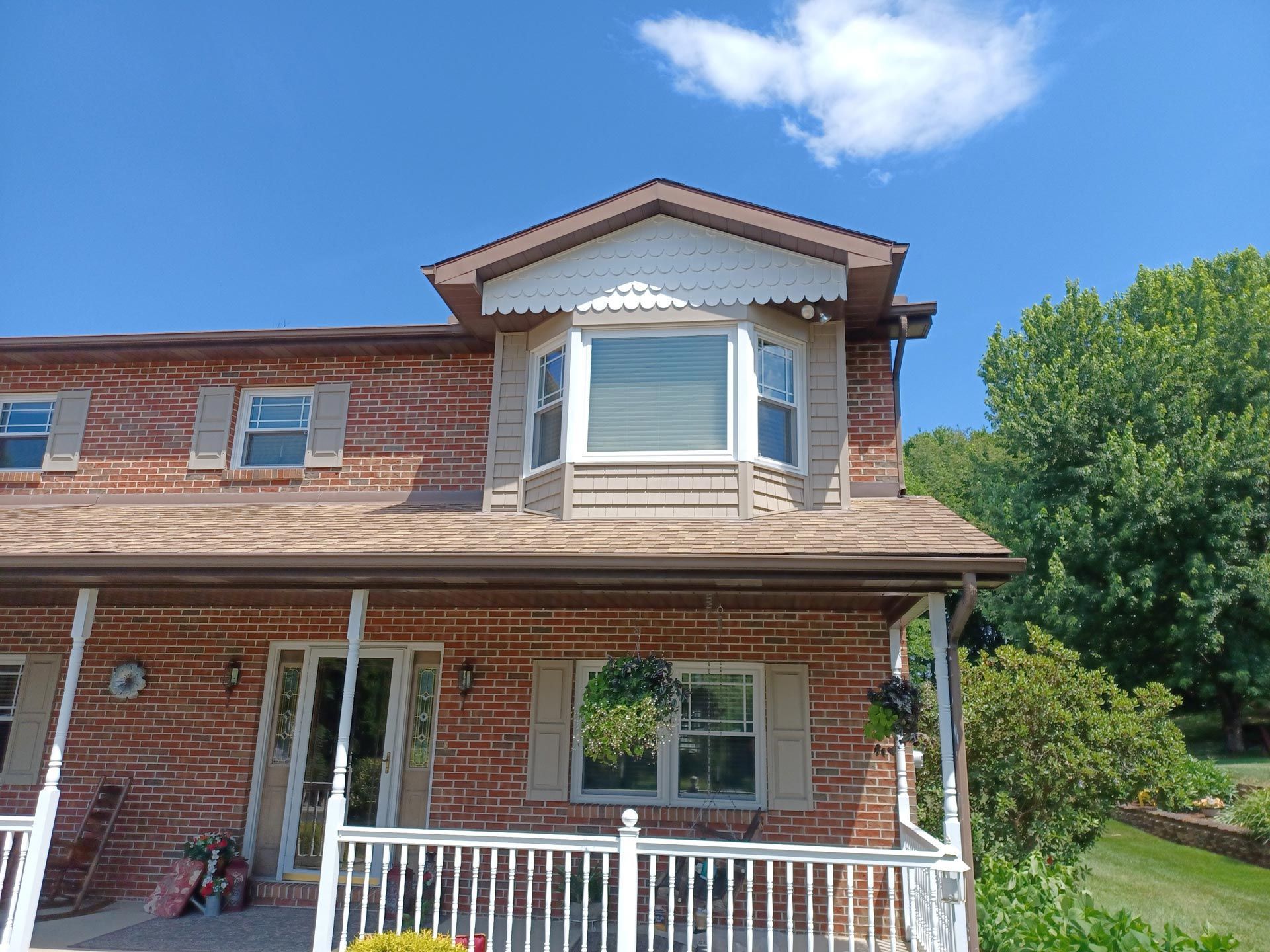 A brick house with a porch and a large window - Window Installation in Lower Burrell, PA