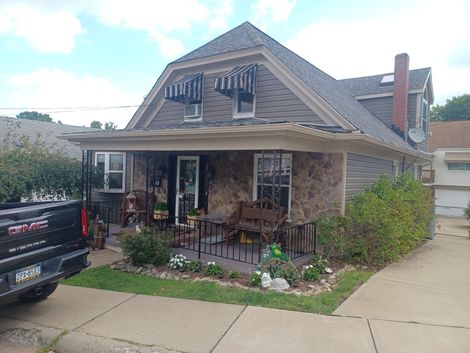 A truck is parked in front of a house with a porch - Window Installation in Lower Burrell, PA