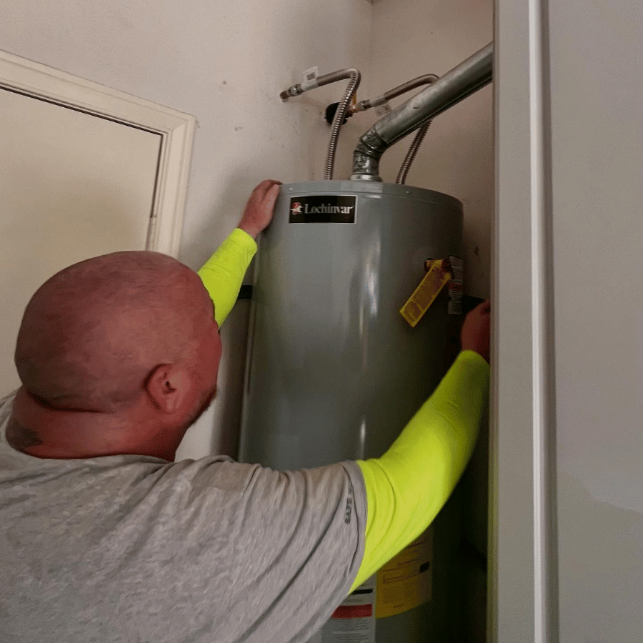 Technician inspecting a water heater in a small utility closet
