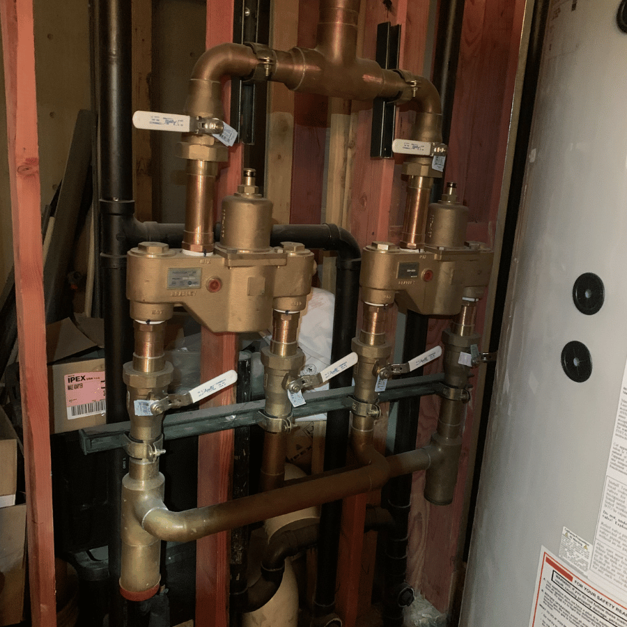 Brass plumbing pipes and valves inside a utility closet or wall cavity