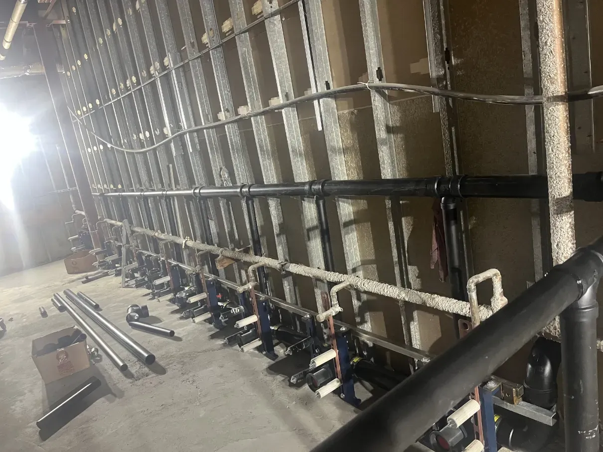Interior wall with exposed pipes and wiring in a dim construction or utility space