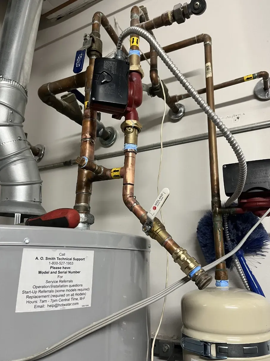 Residential boiler and copper pipes with valves in a basement utility area