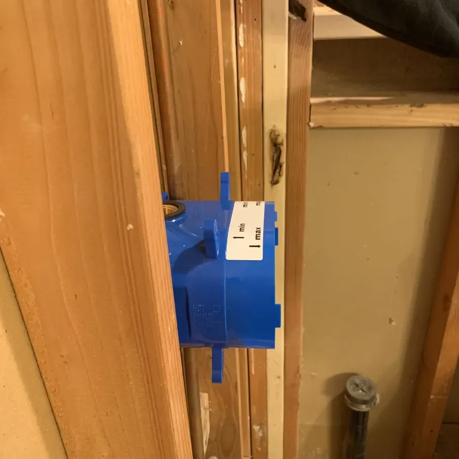 Blue electrical box mounted in a wooden wall cavity during renovation