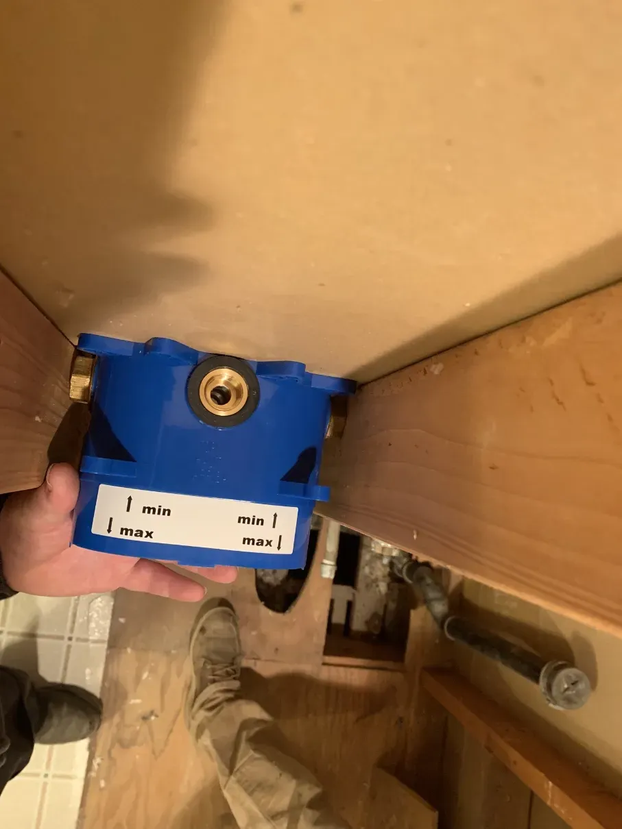 Hand holding a blue package inside a cardboard box, viewed from above.