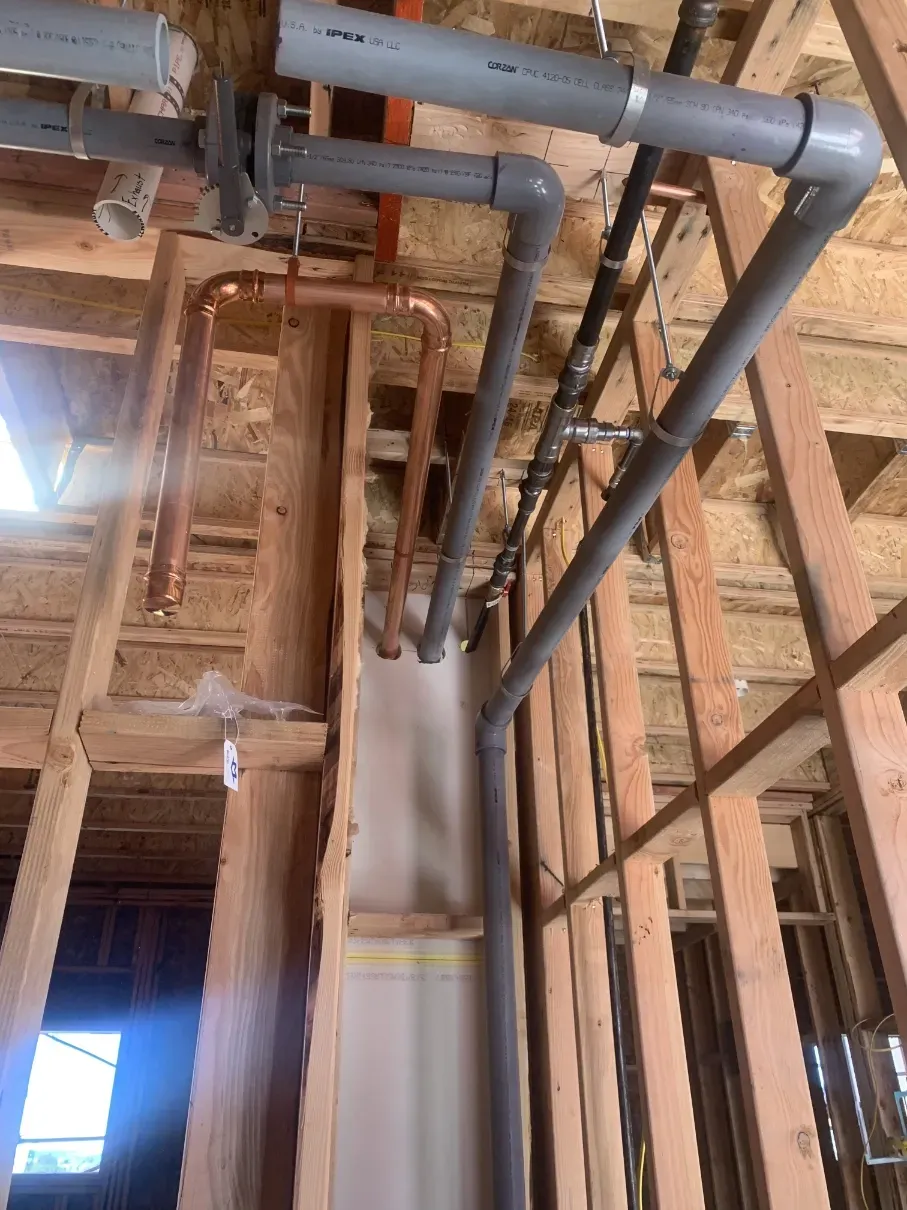 Exposed ceiling pipes and wooden framing inside a building under construction