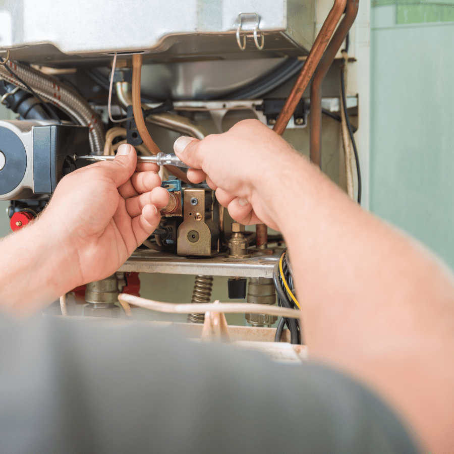 Technician adjusts boiler with a wrench, focusing on pipes and components, ensuring proper function and maintenance.
