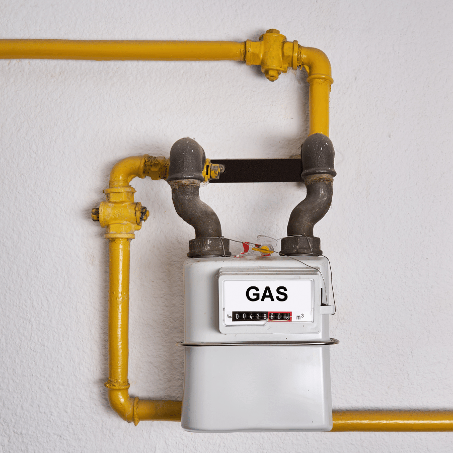 Gas meter with yellow pipes on a white wall, displaying a reading. Essential for monitoring household gas usage.