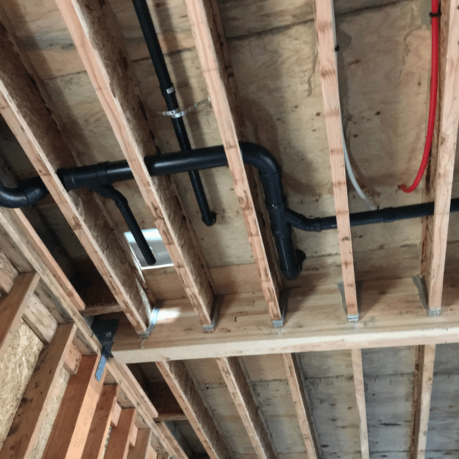 A room featuring exposed pipes and wires hanging from the ceiling, showcasing an industrial design aesthetic.