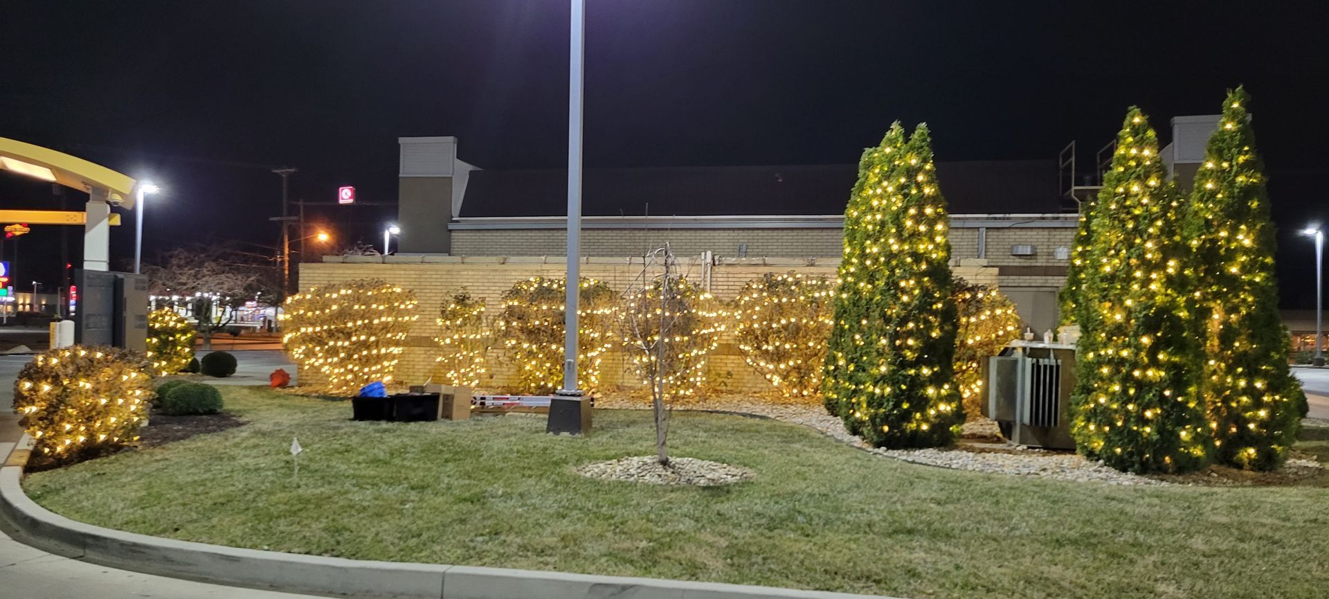 A mcdonald 's parking lot is decorated with christmas lights at night.