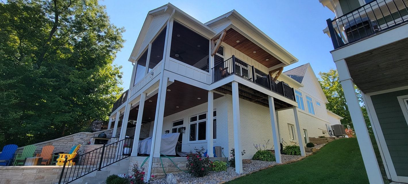 A large white house with a screened in porch and a large deck.