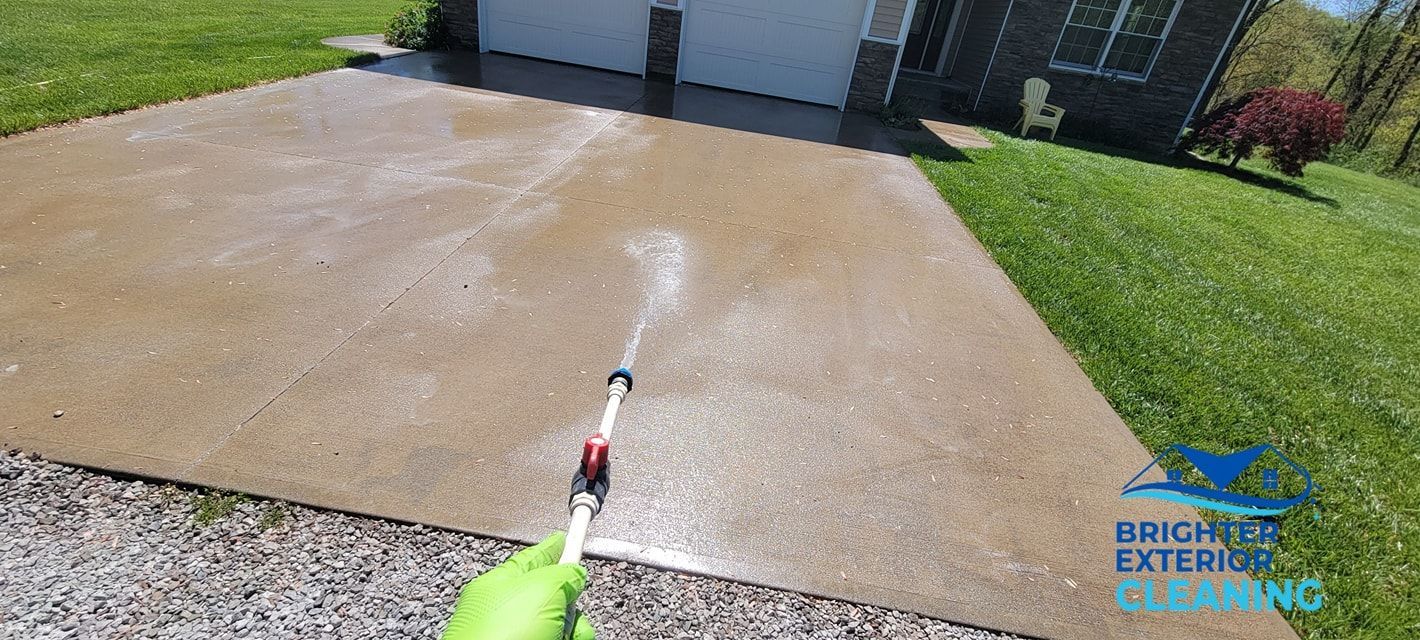 A person is cleaning a driveway with a pressure washer.