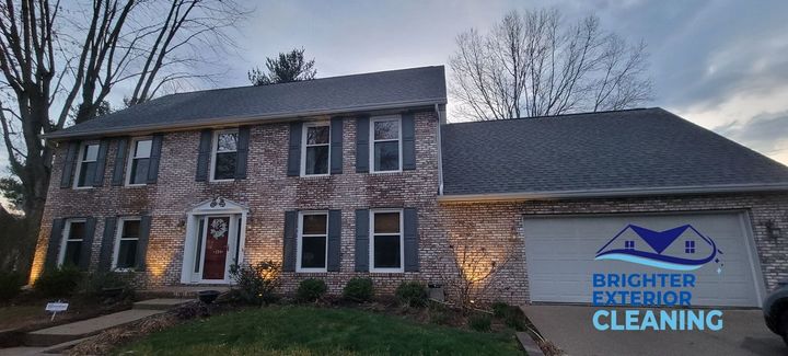 A large brick house is lit up with christmas lights at night.