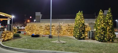 A mcdonald 's parking lot is decorated with christmas lights at night.