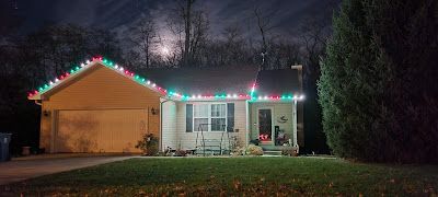 A house with christmas lights on the roof at night.