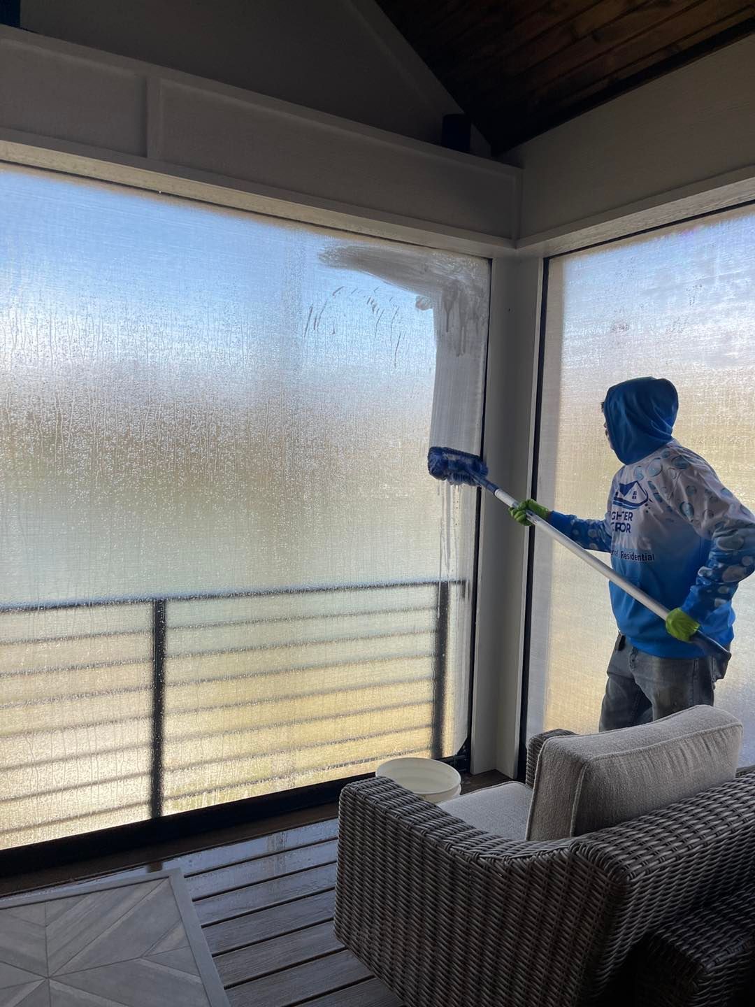 A man in blue overalls is cleaning a window with a sponge.