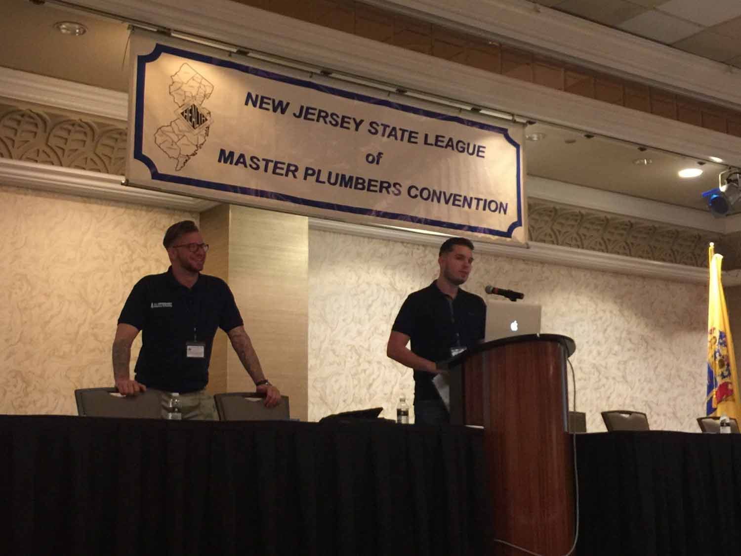 Two men giving a presentation at the New Jersey State League of Master Plumbers Convention.