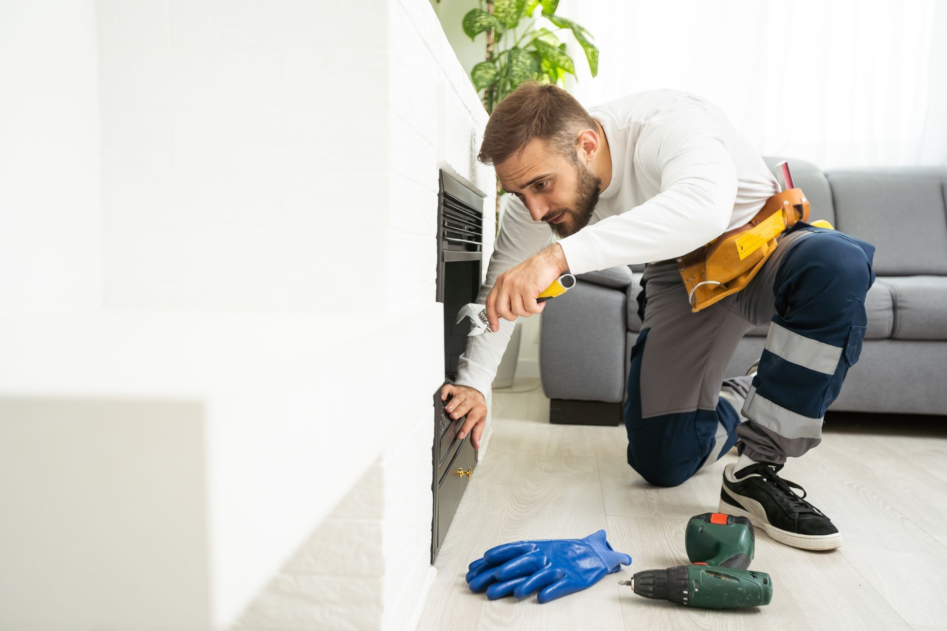 Chimney services technician inspecting fireplace opening with tools during home maintenance.