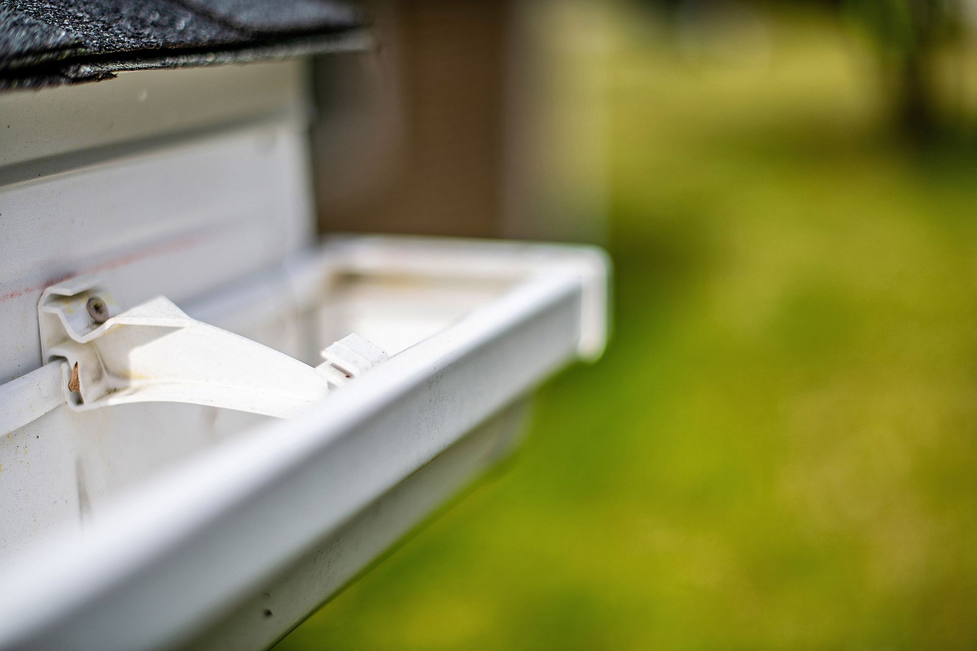 Gutter services showing close-up of damaged white gutter bracket needing repair on home exterior. Gutter services showing close-up of damaged white gutter bracket needing repair on home exterior.