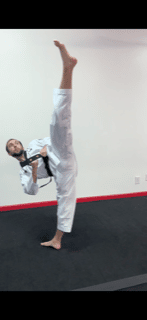 Man in martial arts uniform performing a high kick.