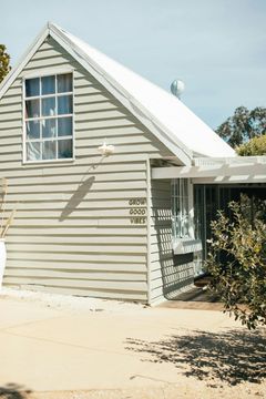 Gray clapboard cottage with a white roof and window, on a sunny day.