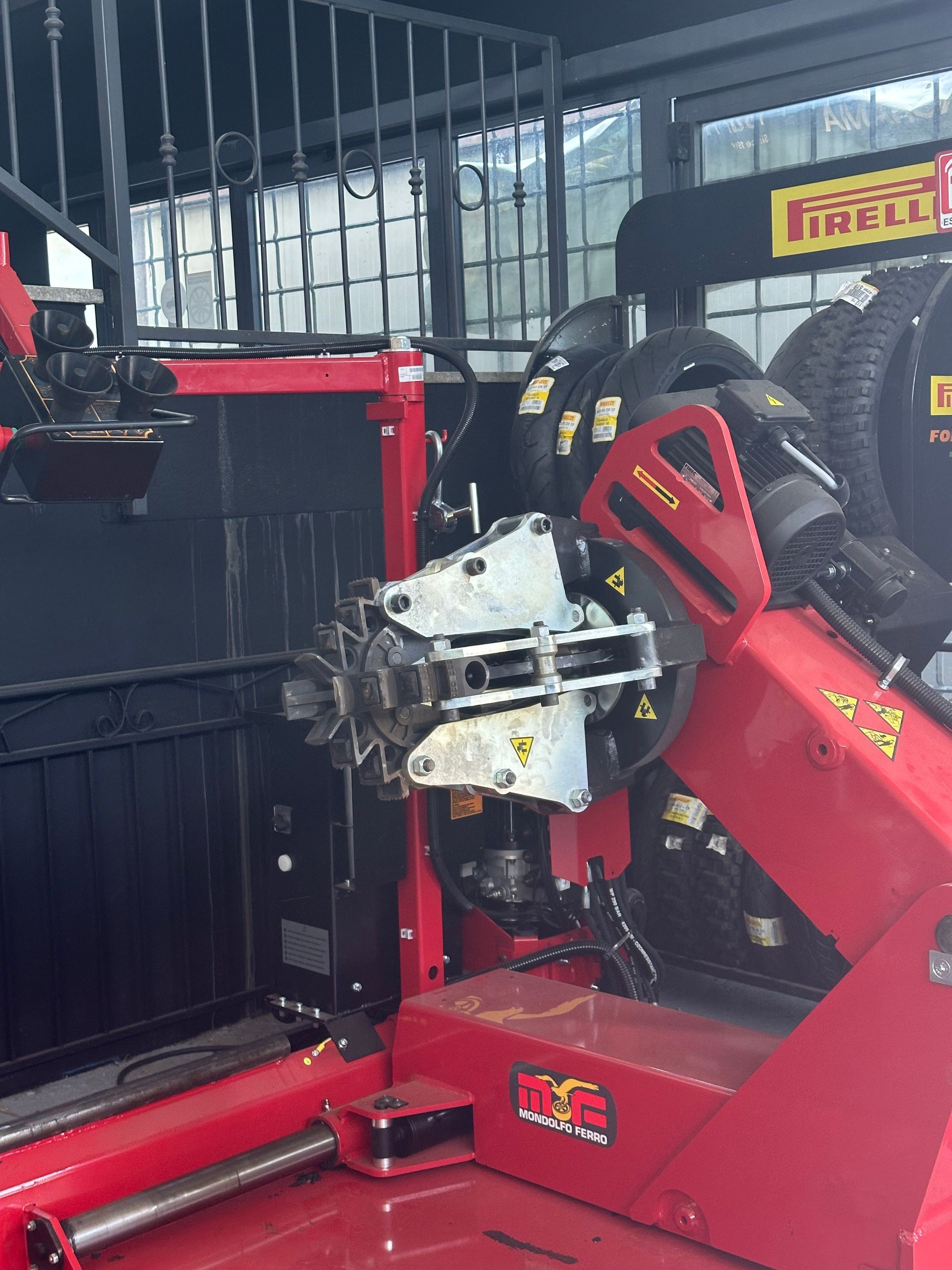 Macchina rossa per il cambio gomme in un garage, con pneumatici visibili sullo sfondo.