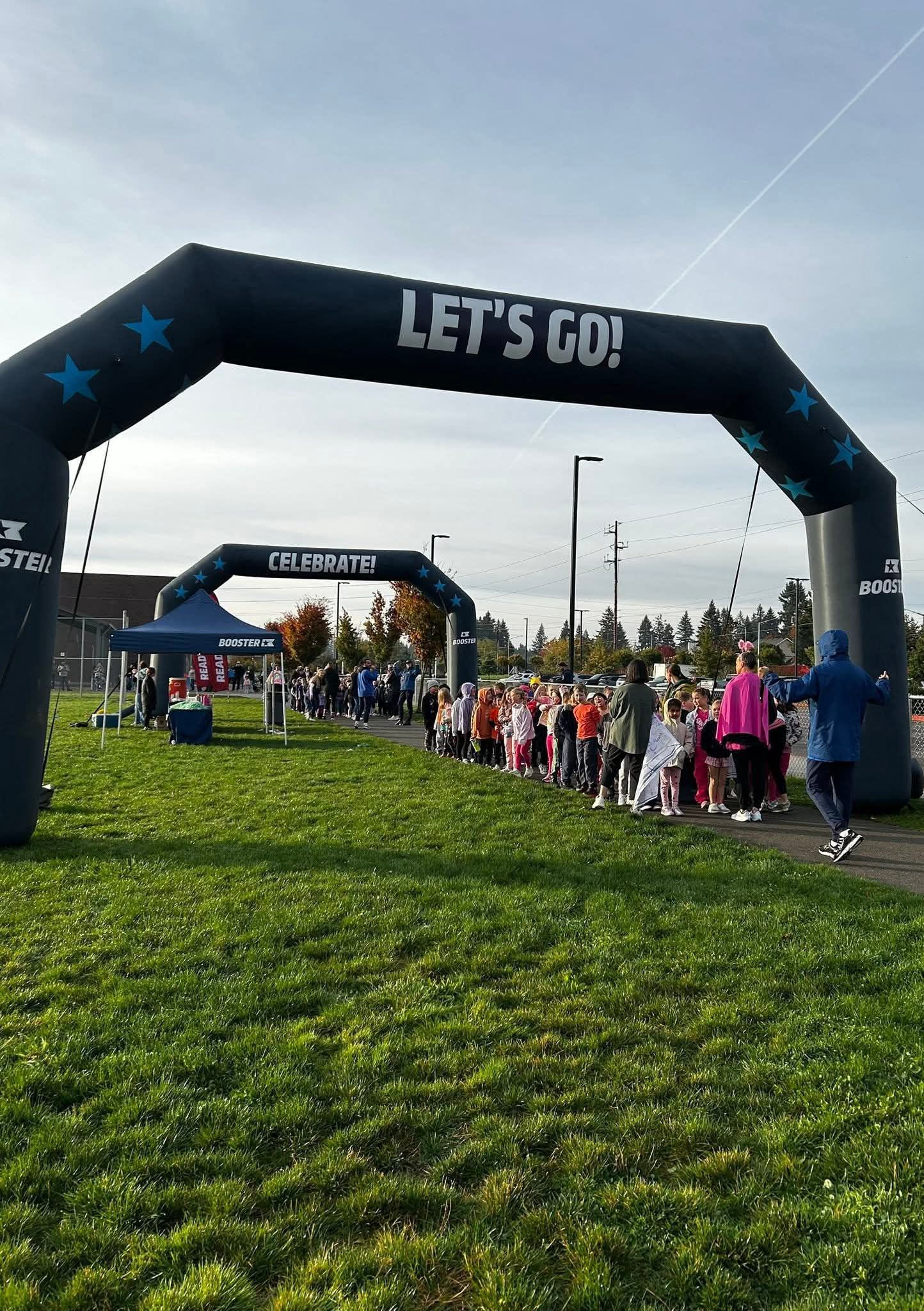Runners at the starting line of a race under an inflatable arch that reads