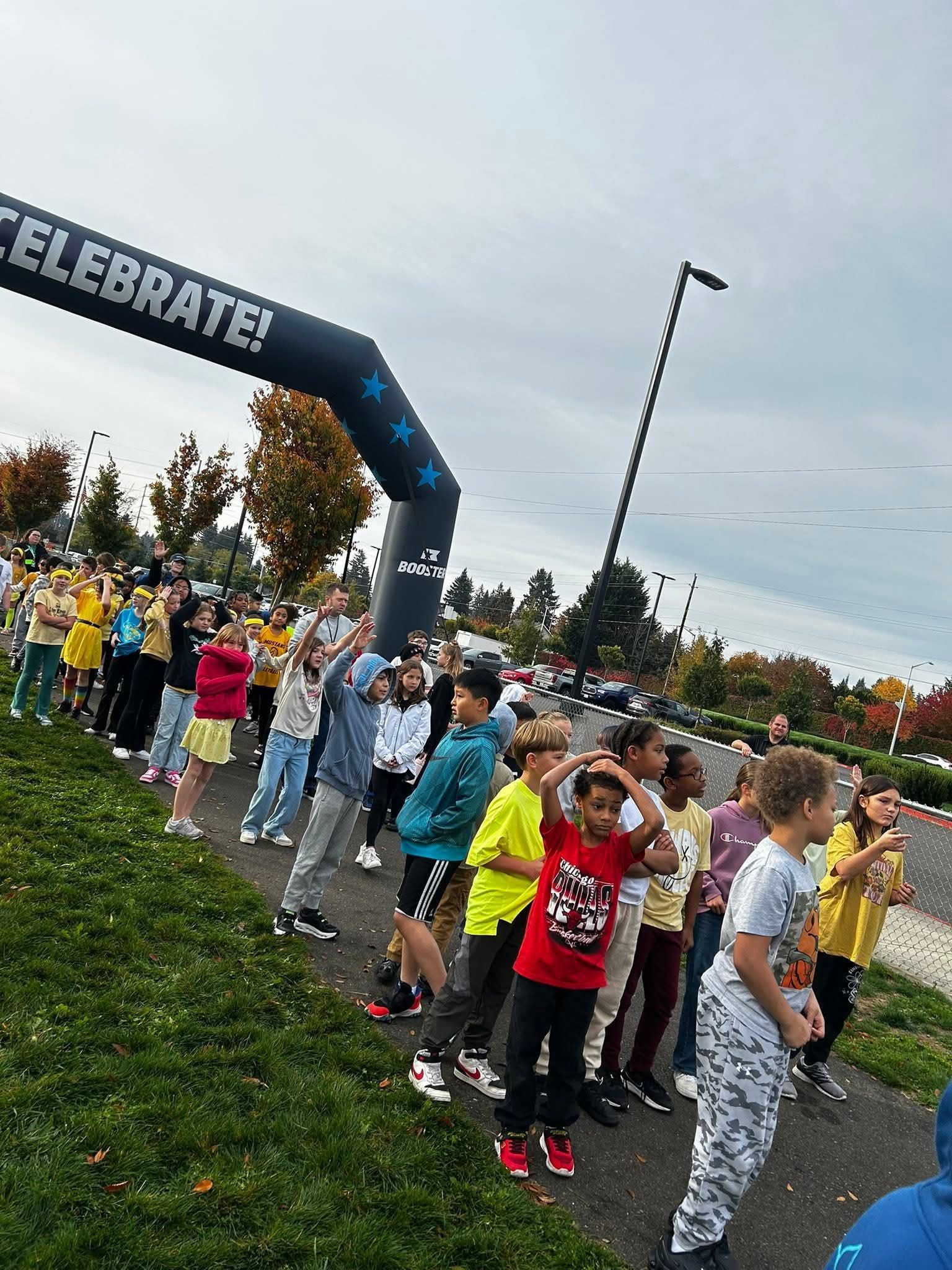 Group of children at a race starting line under an archway that says