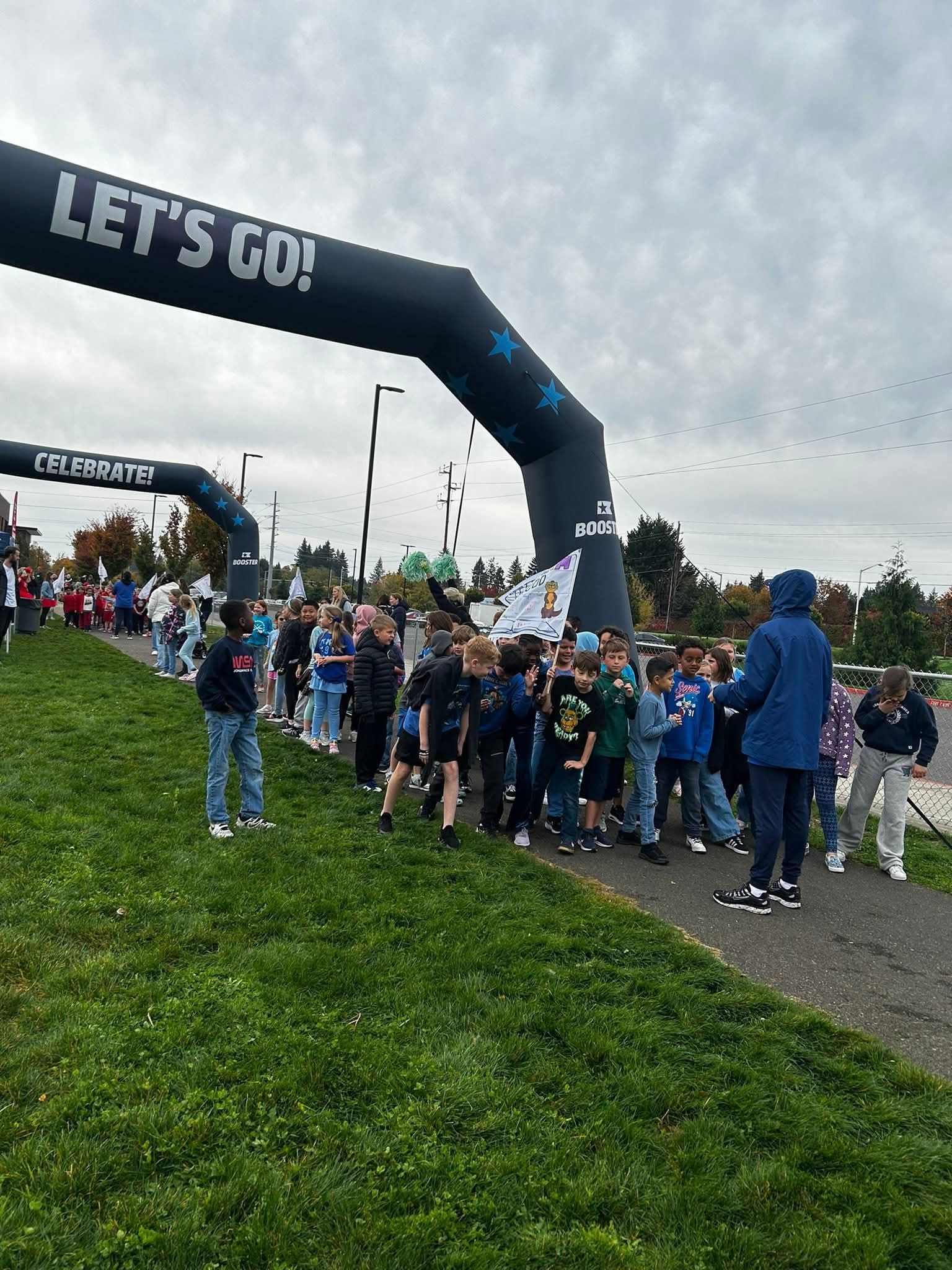 Children line up at a race start line under an archway that says