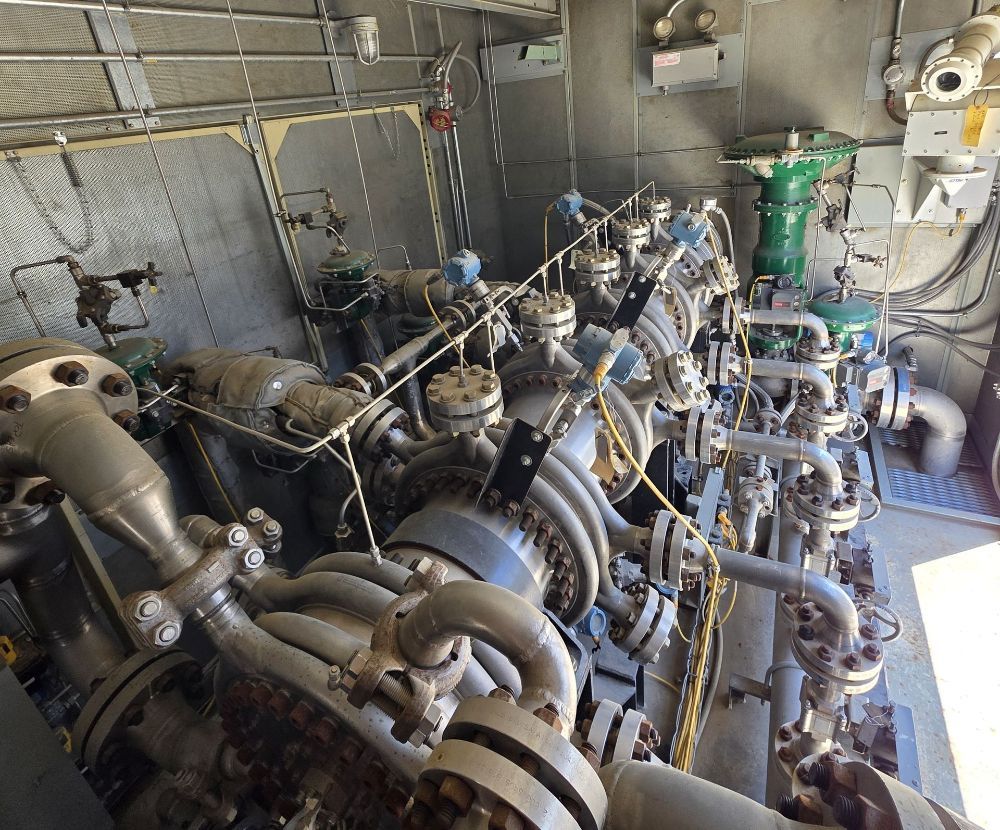 Industrial engine room packed with pipes, valves, and machinery in a metal-walled facility