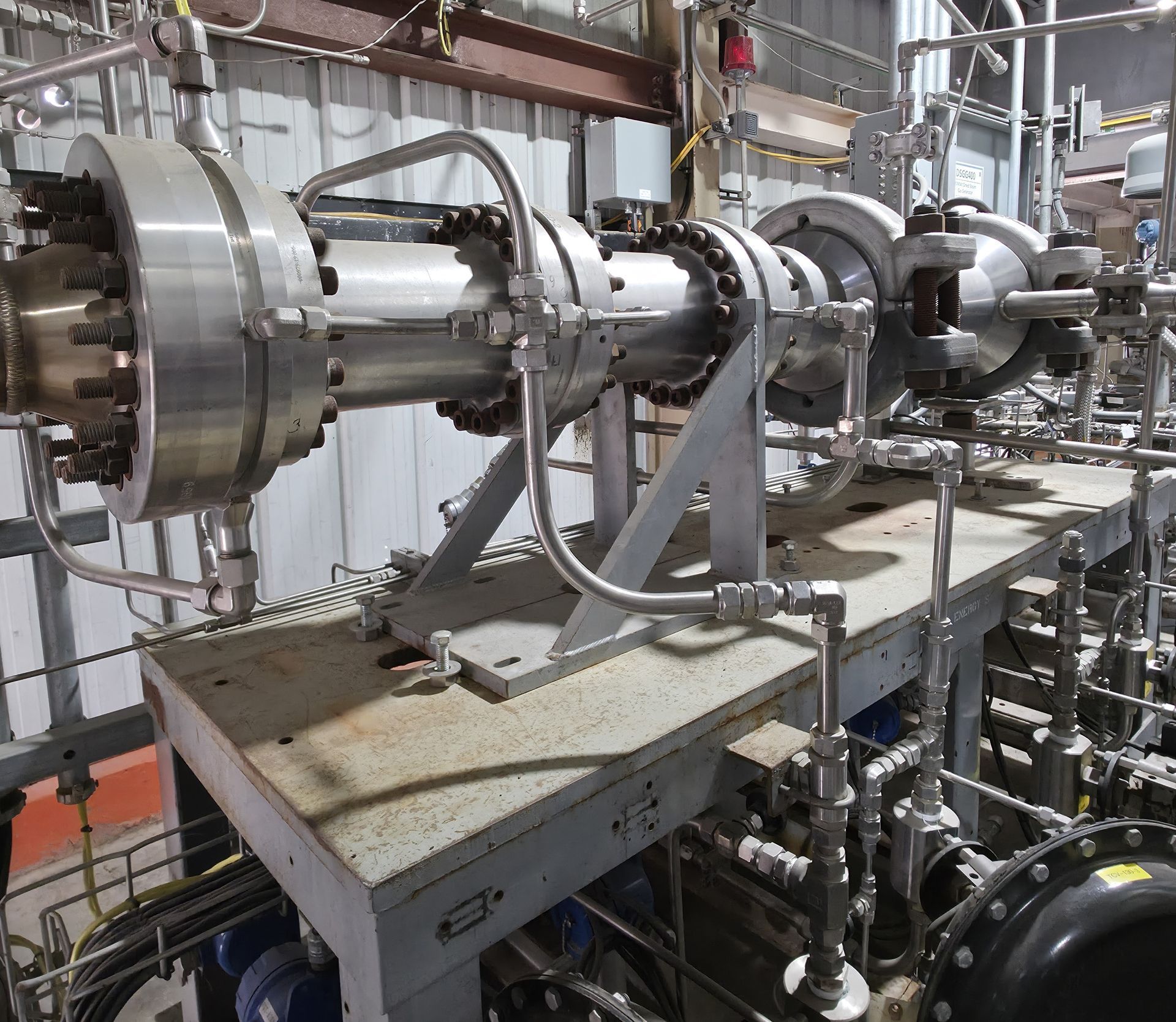 Industrial stainless-steel machinery with pipes and supports inside a factory setting