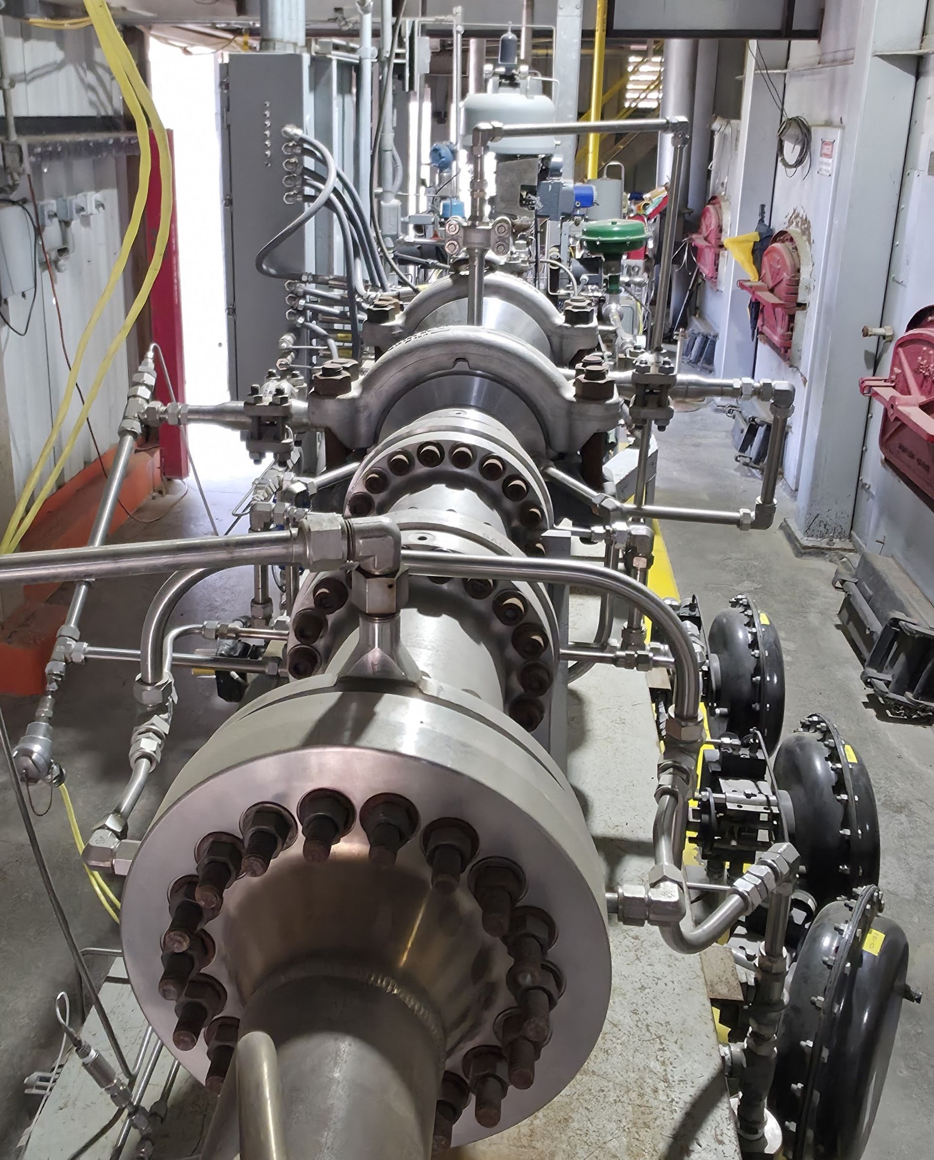 Industrial machinery with large metal turbines and pipes in a factory setting