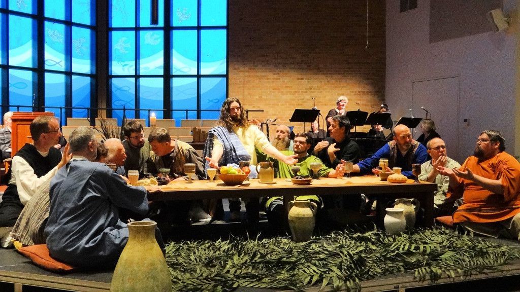 A group of people are sitting at a long table in front of a large window.