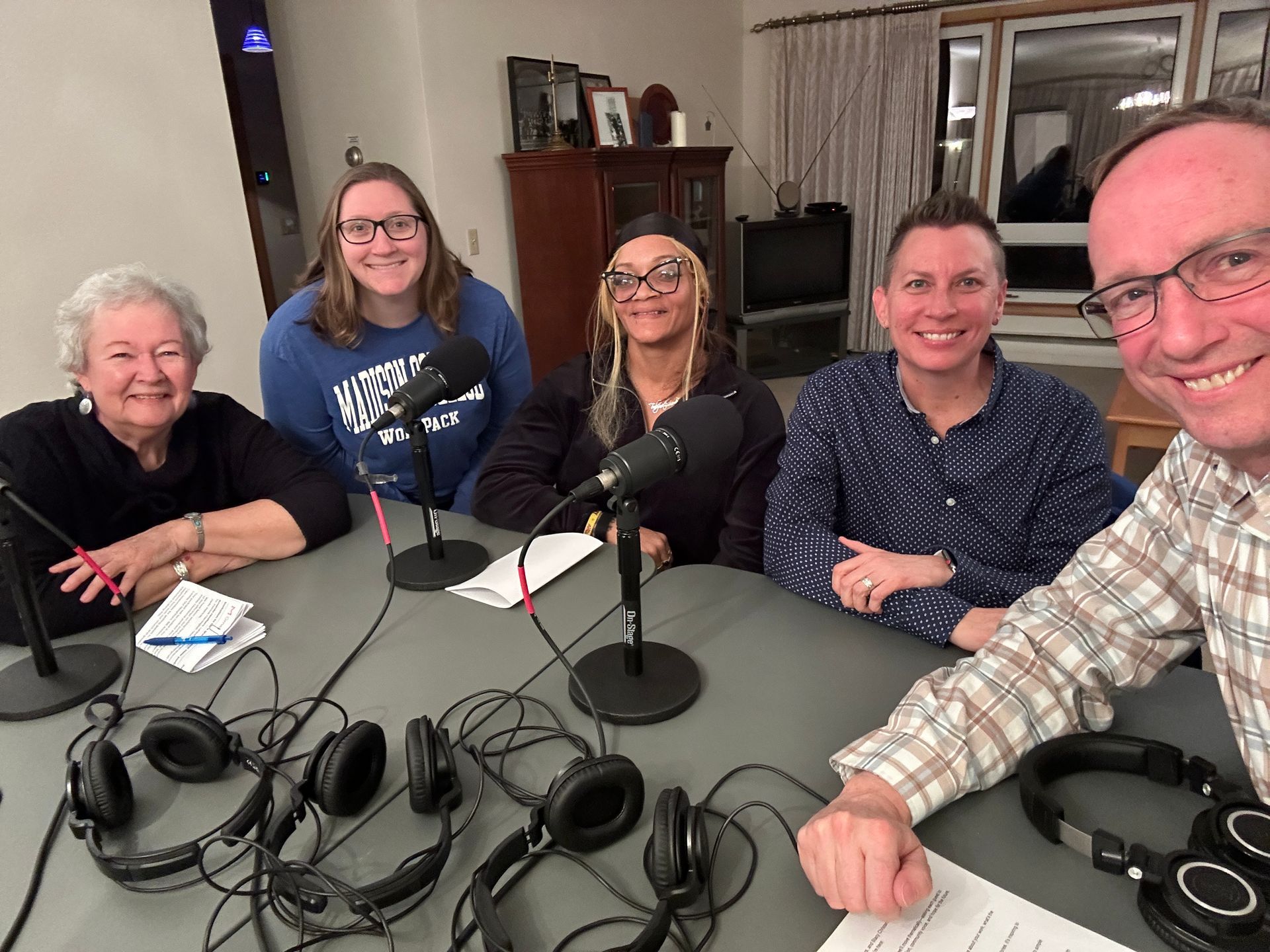 A group of people are sitting around a table with microphones and headphones.