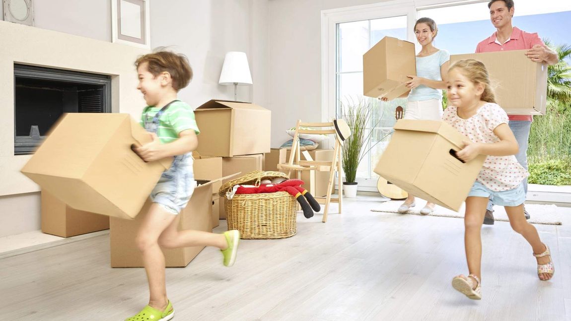 Family carrying cardboard boxes, moving into a new home.