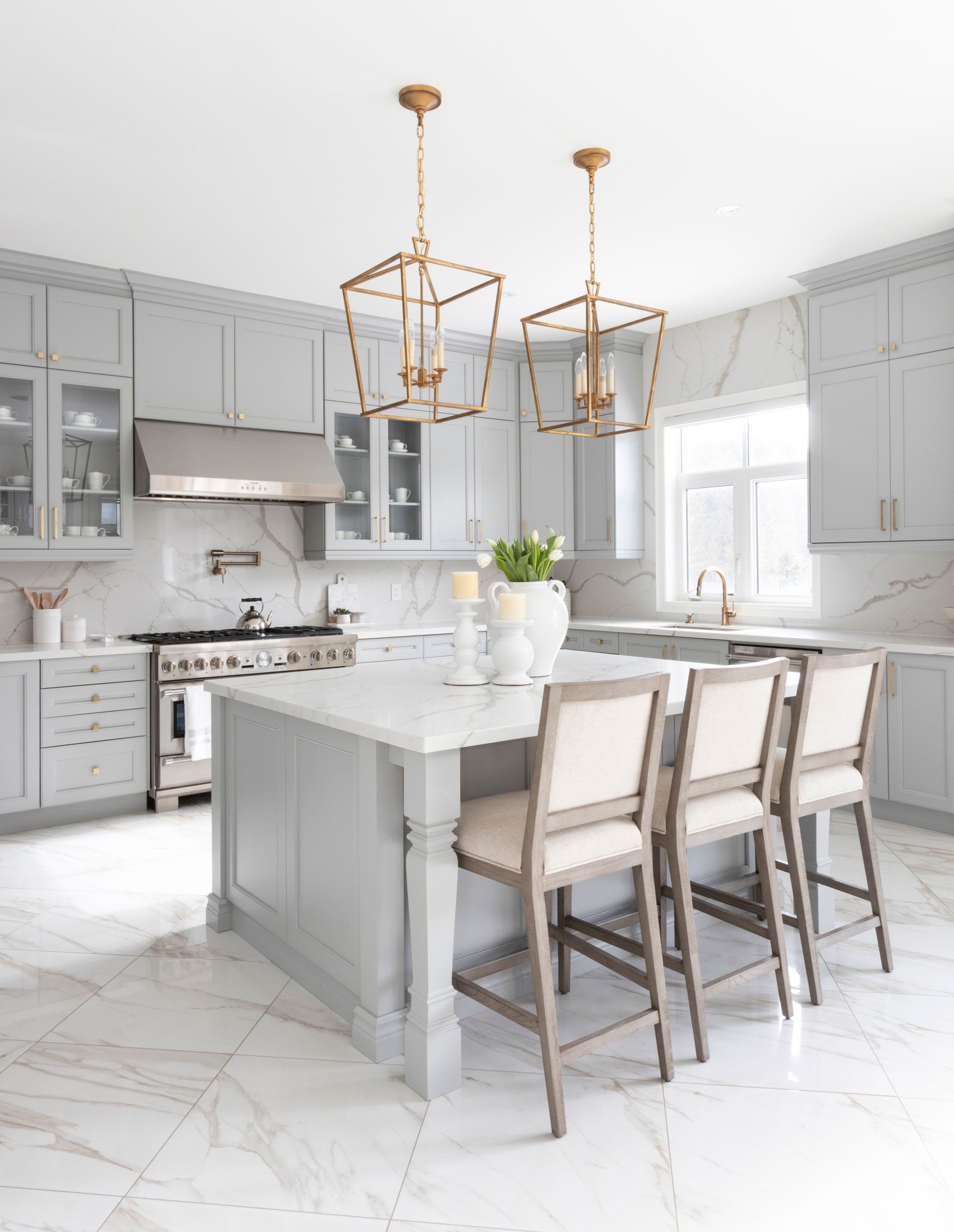 A kitchen with white cabinets , a large island , and a stove.