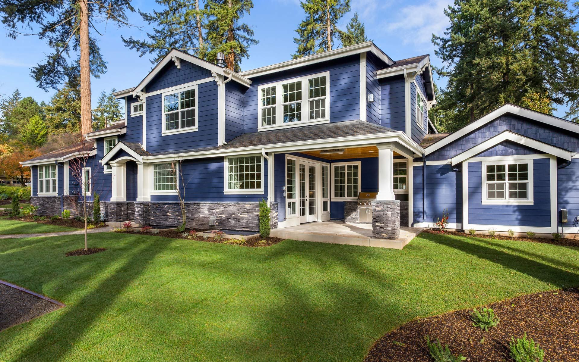 A large blue house with a lush green lawn in front of it.