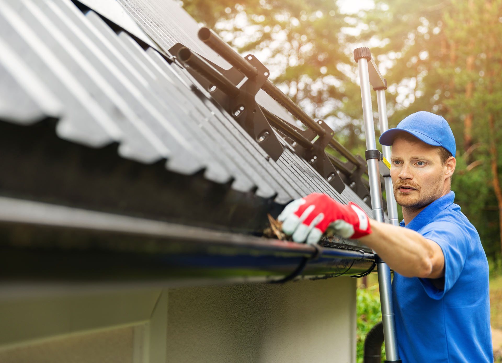 A man is cleaning a gutter on the roof of a house.