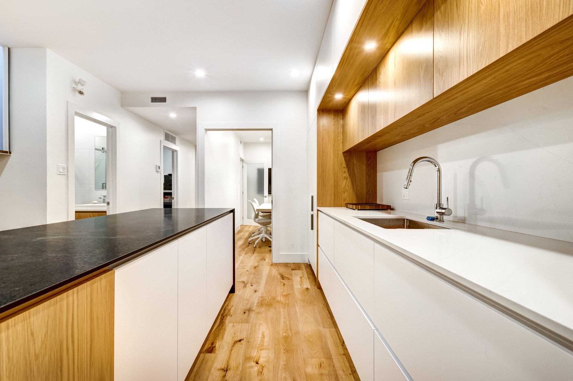 A kitchen with white cabinets , black counter tops , and wooden floors.