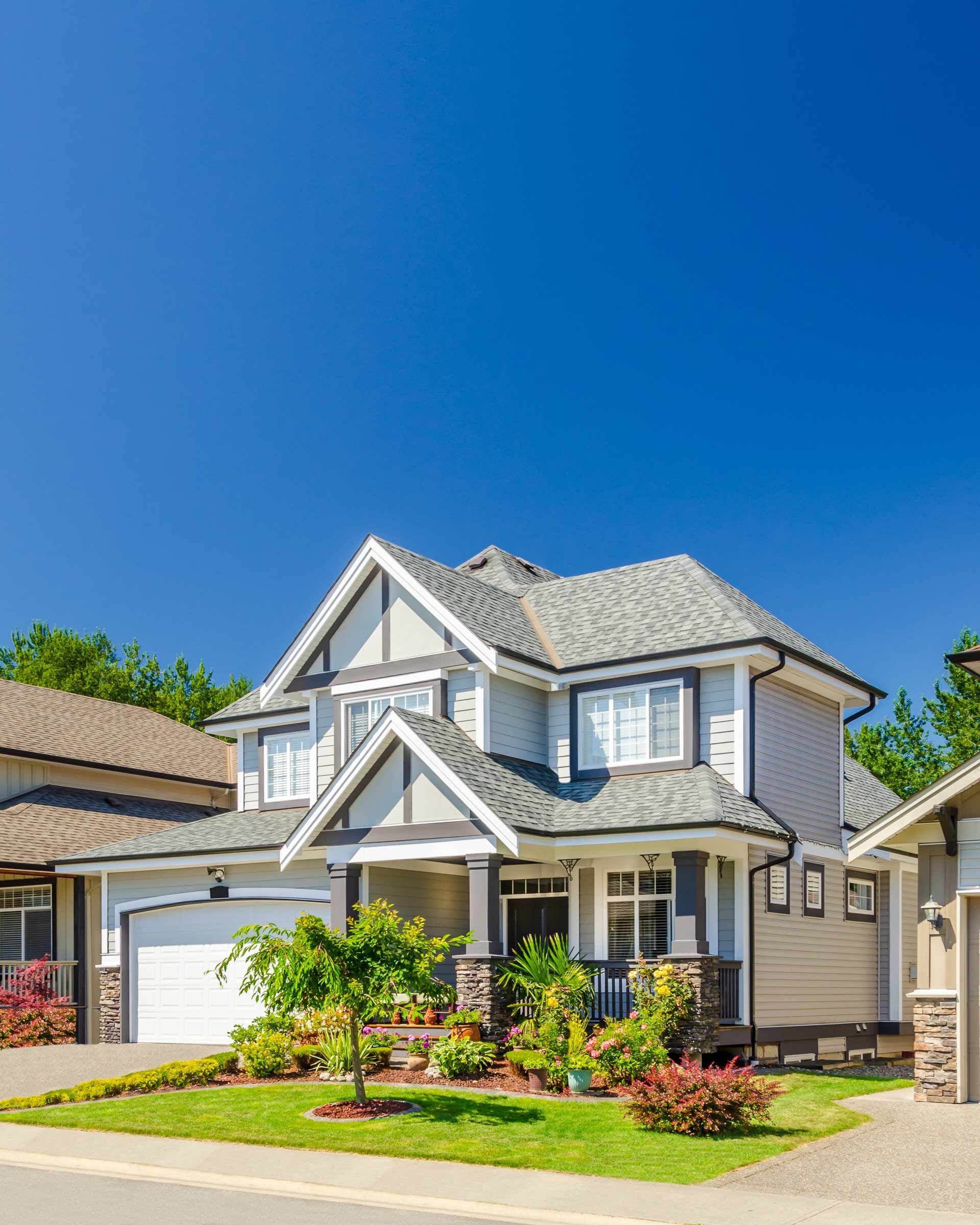 A large house is sitting on top of a lush green lawn in a residential neighborhood.