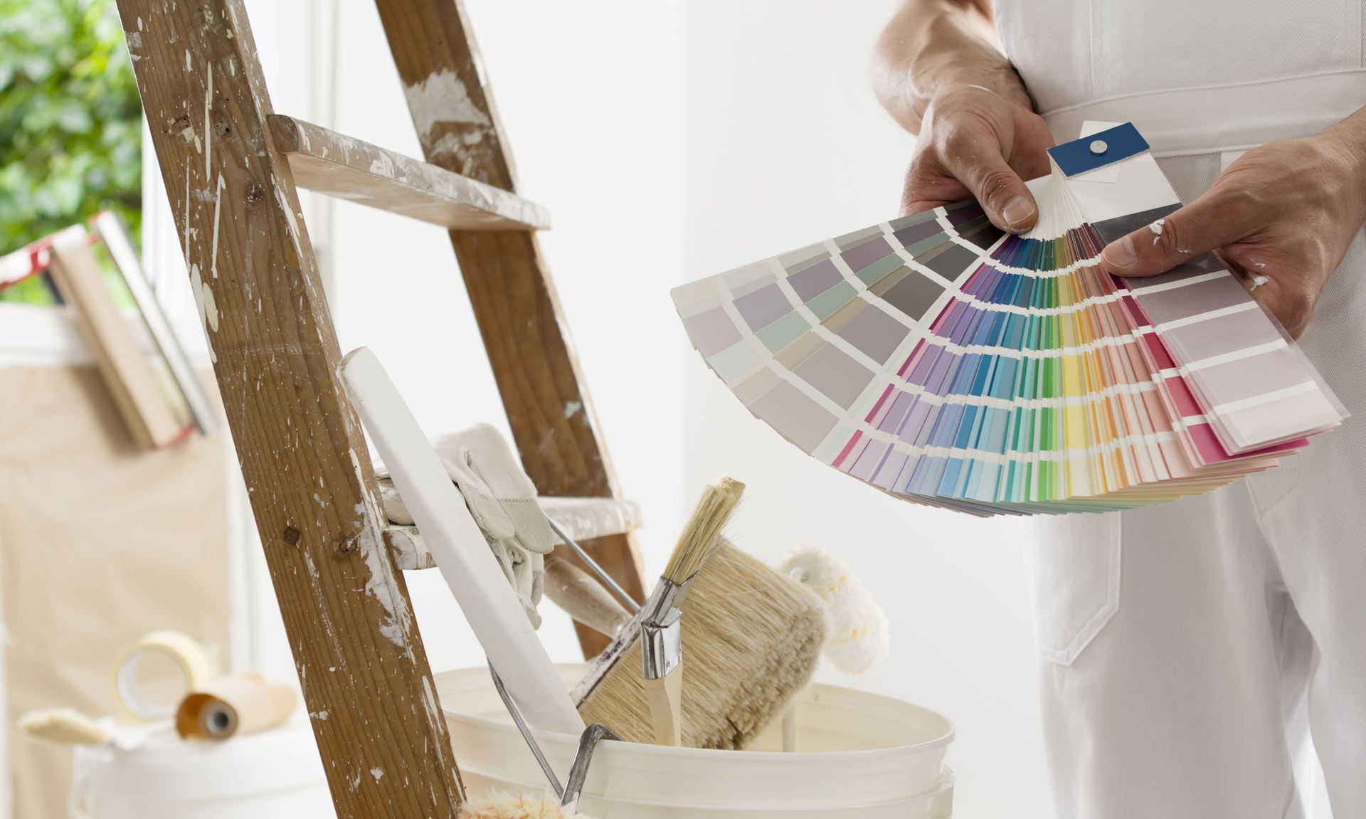 A person is holding a color palette in front of a ladder.