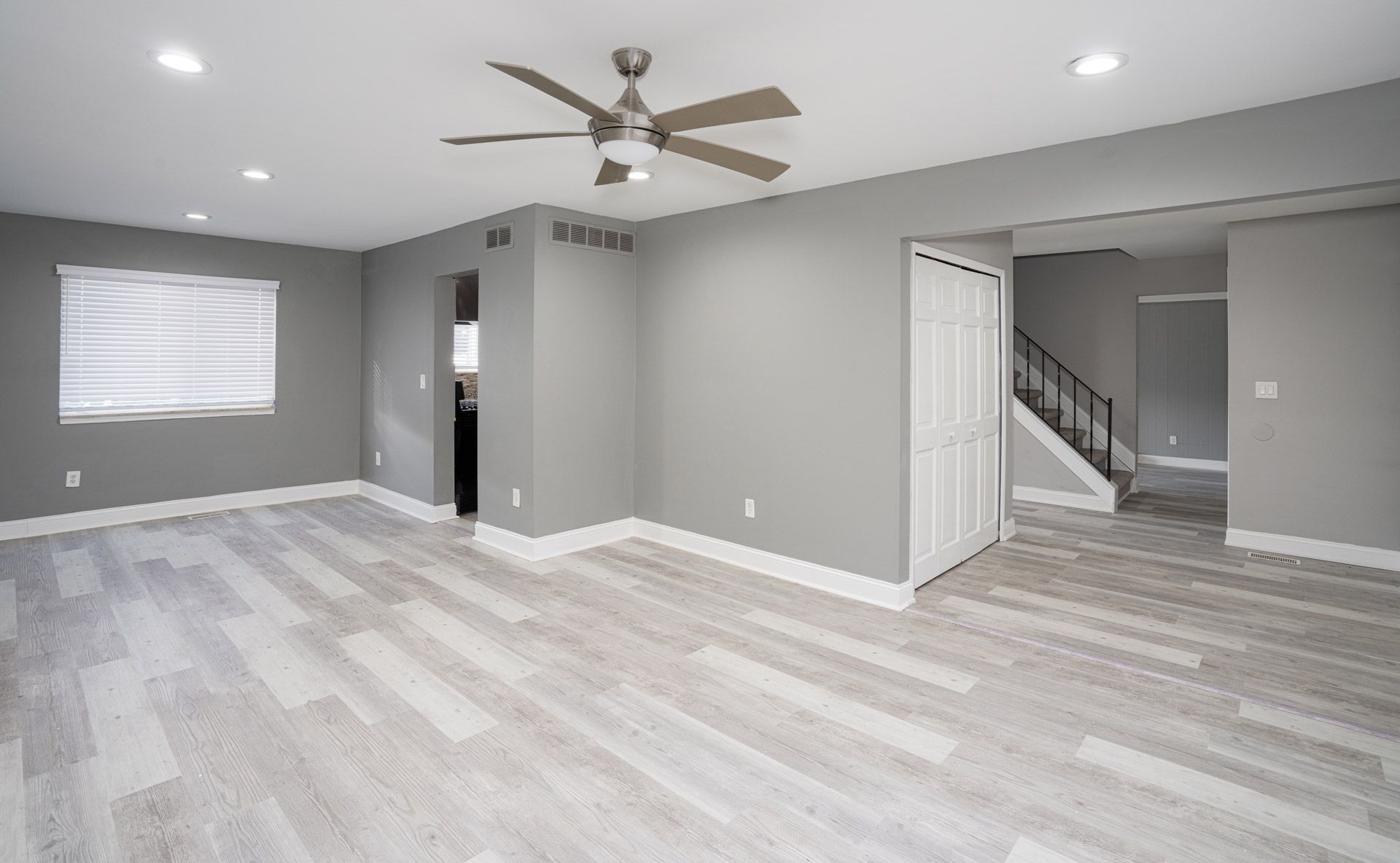 An empty living room with hardwood floors and a ceiling fan.