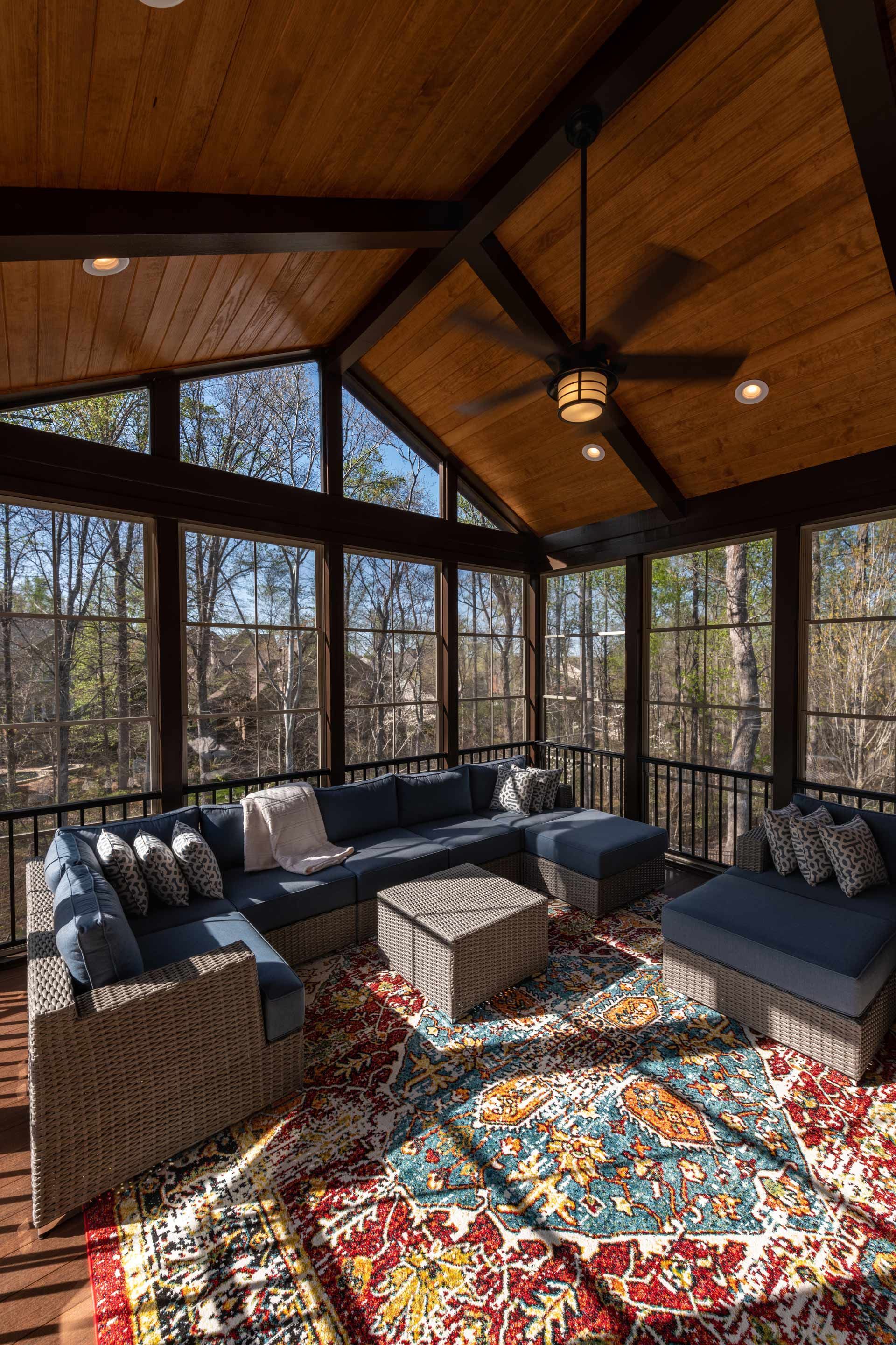A screened in porch with a lot of windows and furniture.