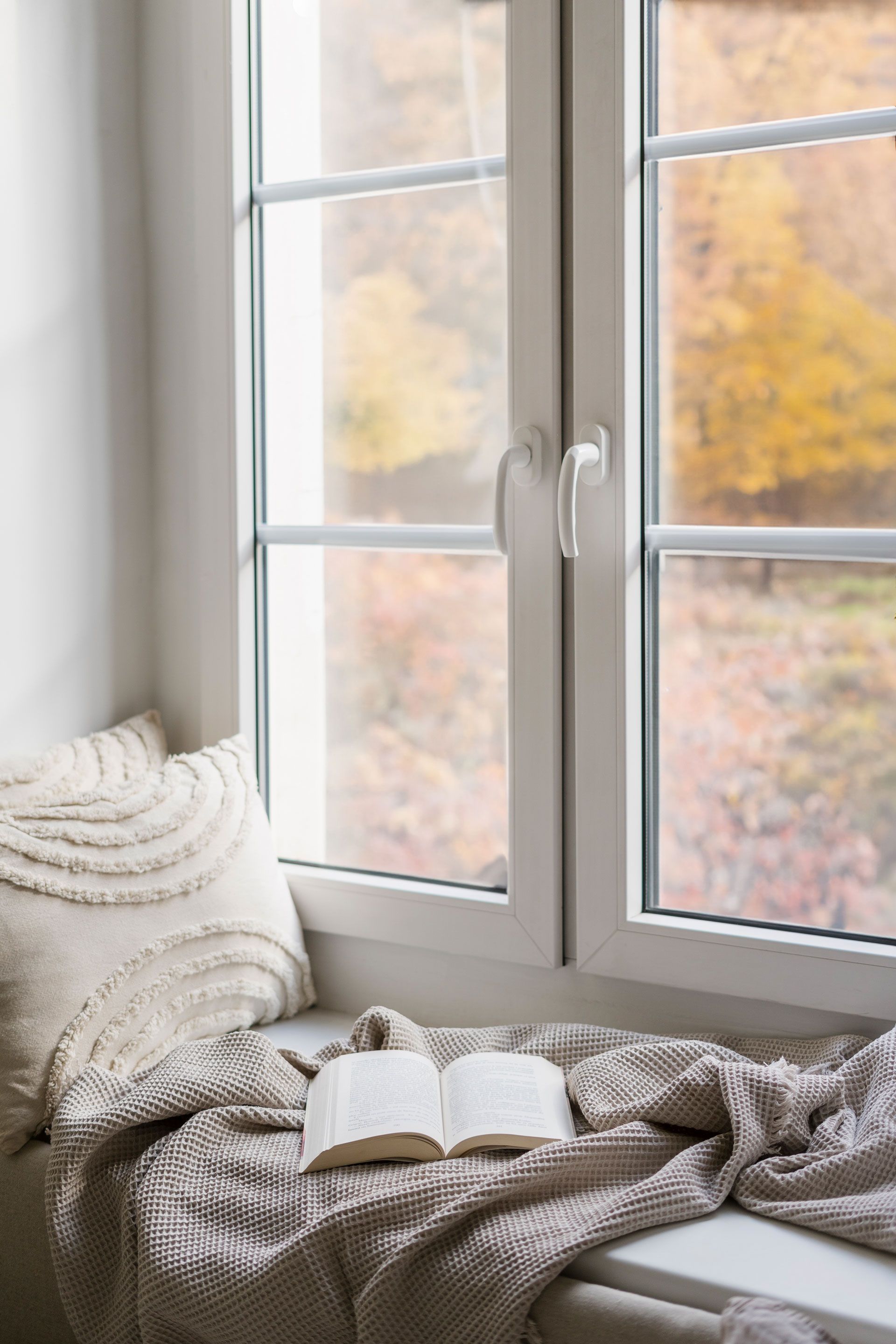 A book is sitting on a window sill next to a window.