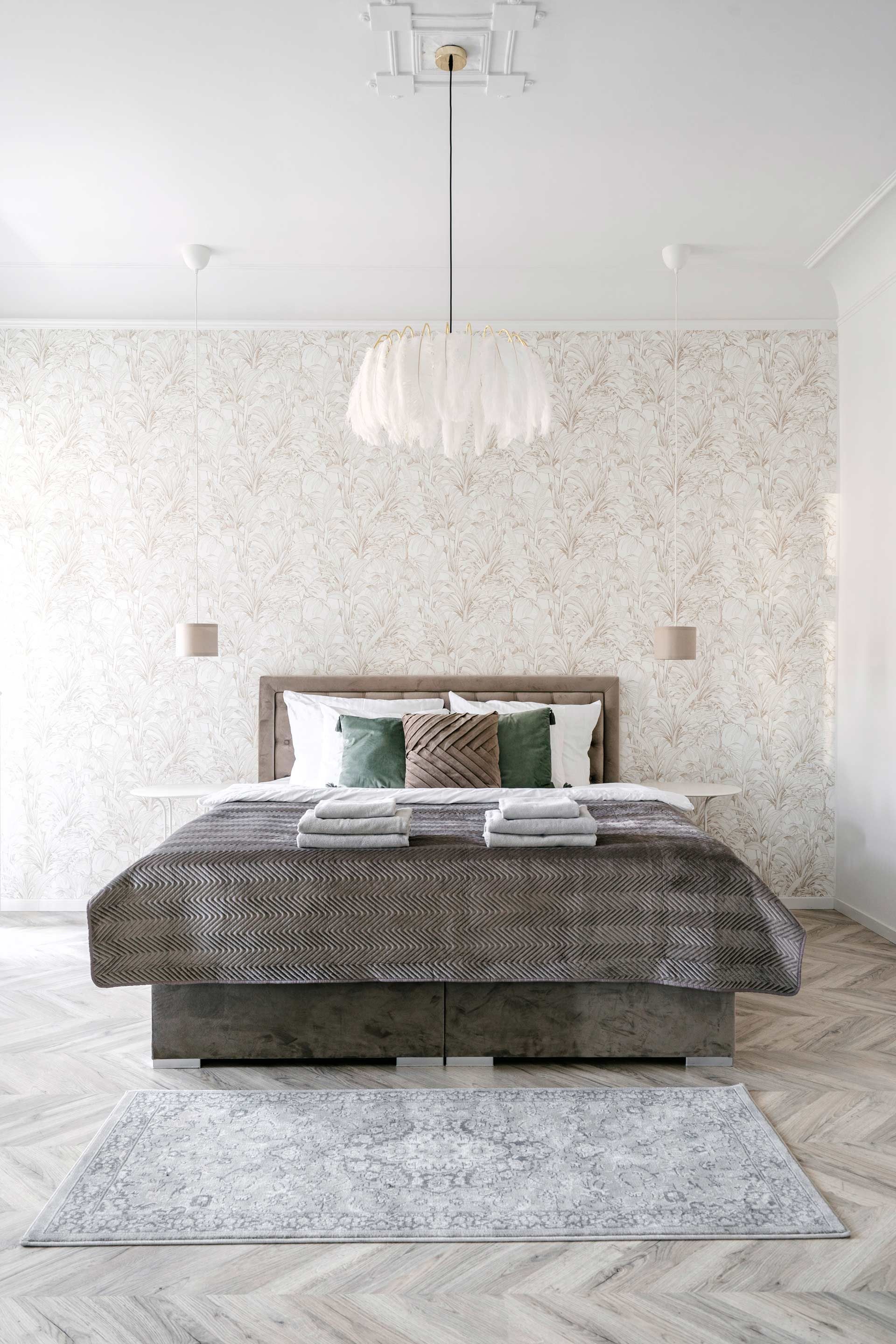 A bedroom with a bed , rug and chandelier.