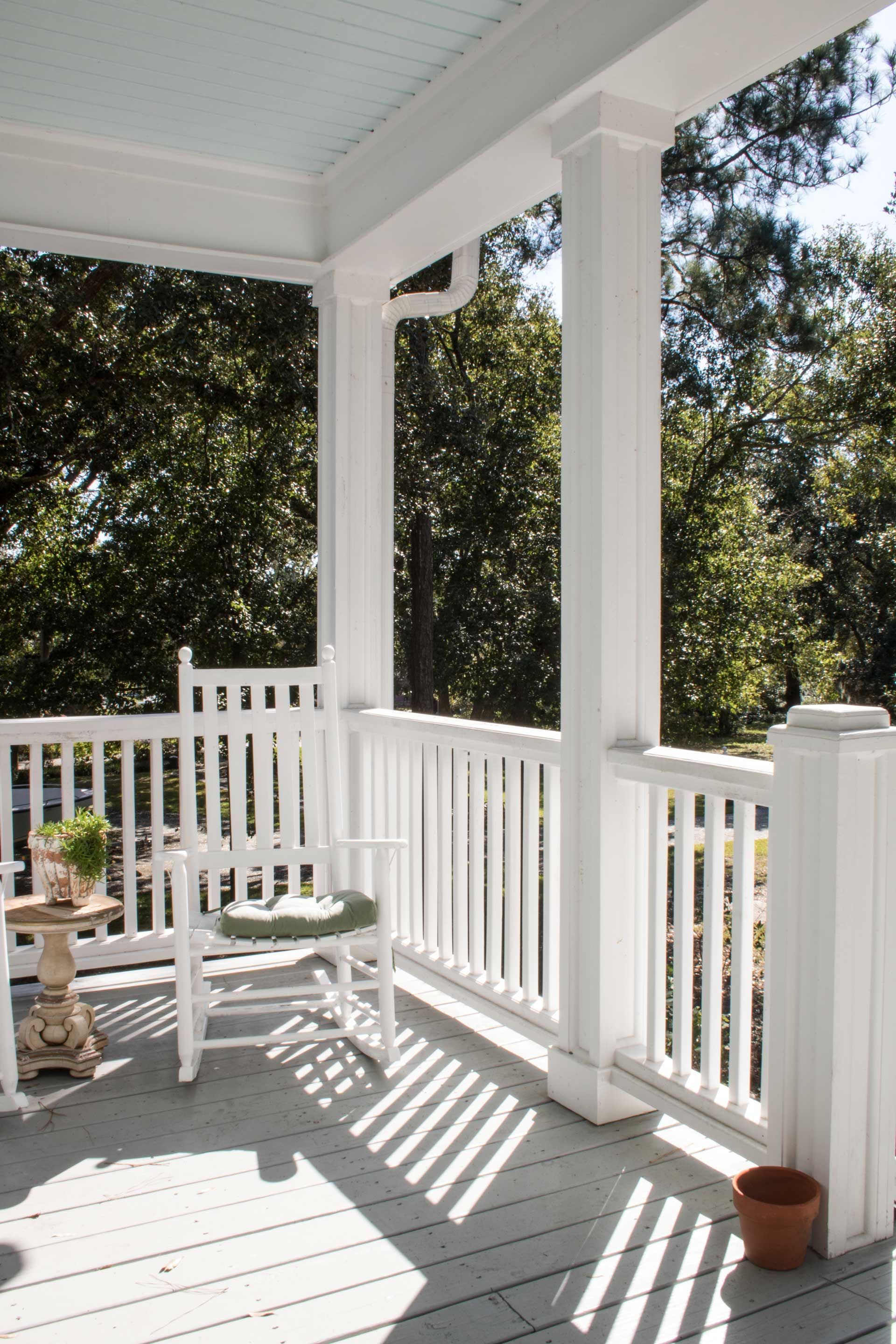 A porch with a rocking chair and a potted plant