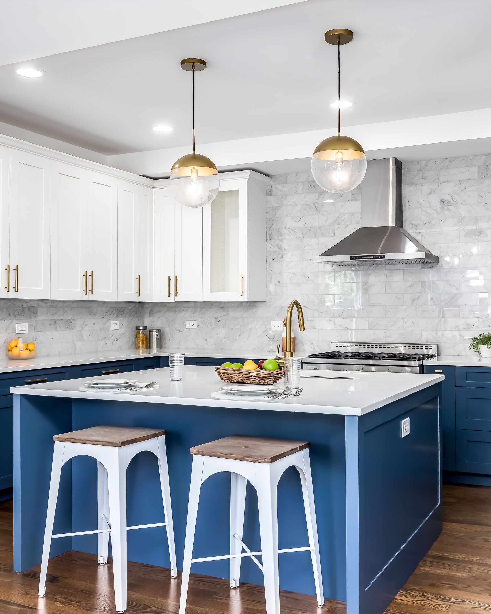 A kitchen with a blue island , white cabinets , stools and a stove.