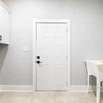 A laundry room with a white door and a white sink.