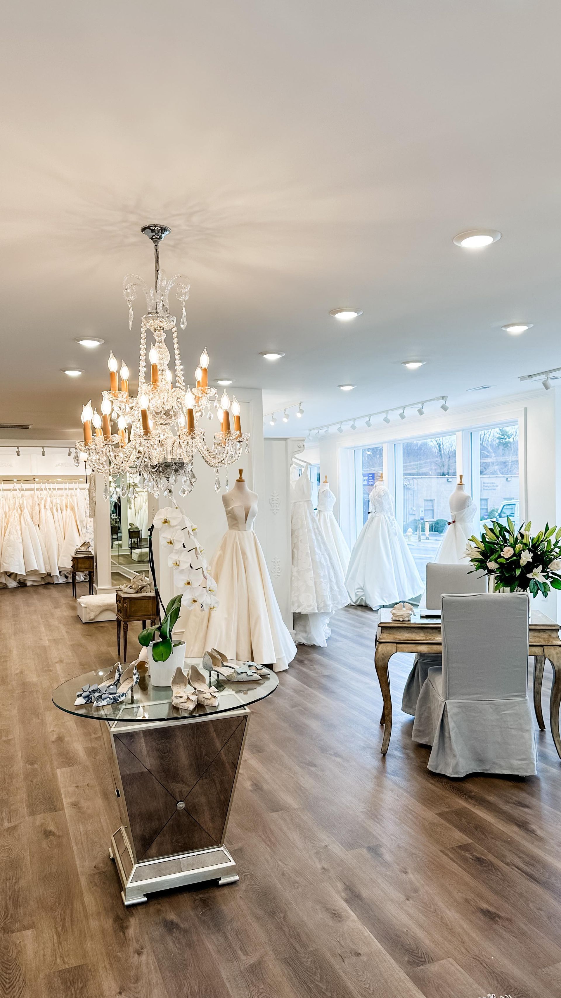 A large room filled with lots of wedding dresses and a chandelier.